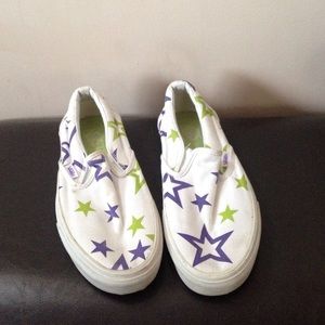 White slip-on Vans with purple and green stars.