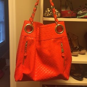 Orange basketweave purse with gold accents.