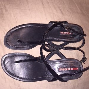 Prada wedge sandals in black patent leather.