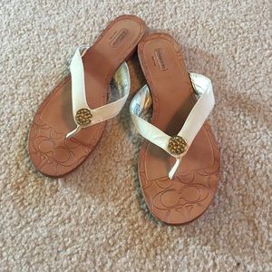 Cream patent Coach flip flops with gold emblem