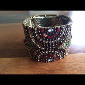 Gold bracelet with red and green stones.