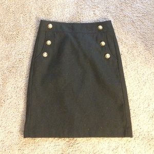 Black pencil skirt with gold button pocket detail.