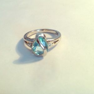 Silver studded ring with blue stone in the middle.