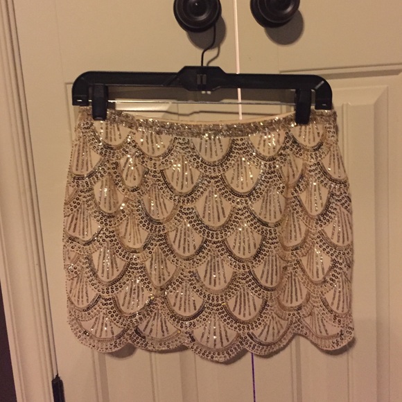 Beige mini skirt with gold sequin design.