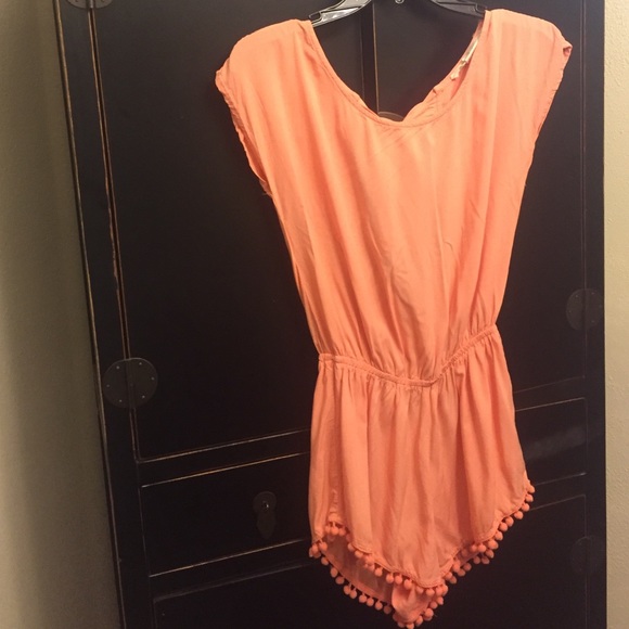 Coral romper with pom poms at the bottom
