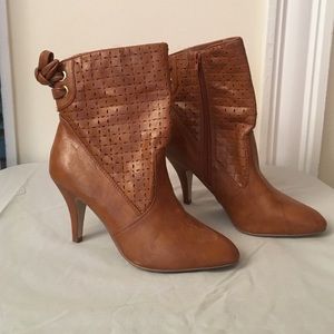 Brown heeled boots, rise above ankle.