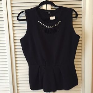 Sleeveless peplum top w/neckline embellishment.