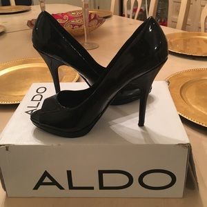 Classic black patent leather peep toe pumps.