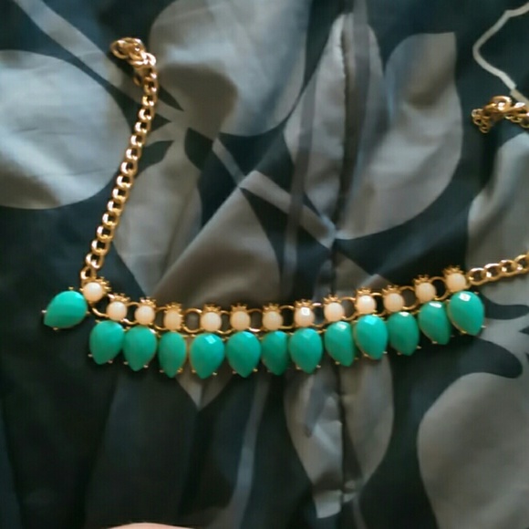 A gold necklace with  a sea glass colored gems
