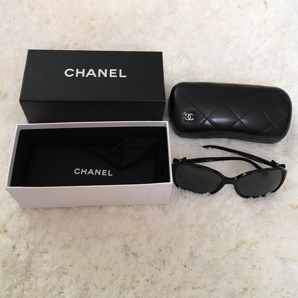 Chanel black sunglasses with gold bow on the side.