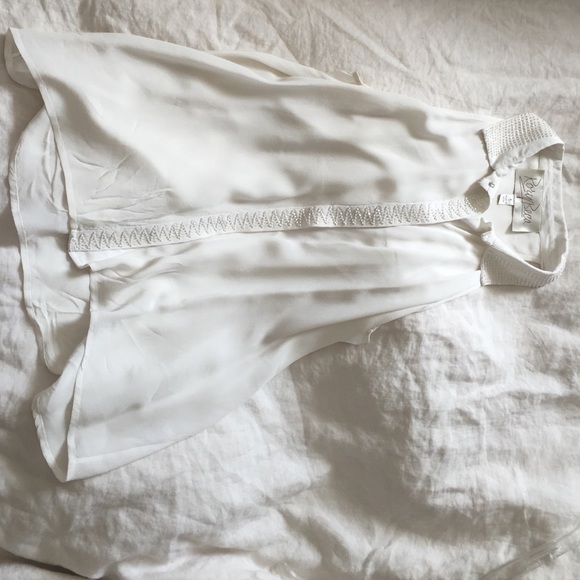 A white silk sleeveless blouse with sequin detail.