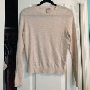 A high-necked, creamy tan sweater.