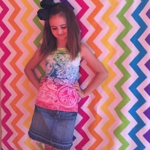 A multi color tank top and a blue jean skirt.