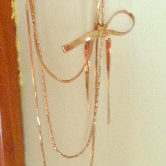 Long gold colored necklace with a bow