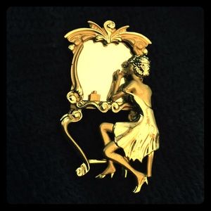 Gold pin with lady looking in makeup mirror