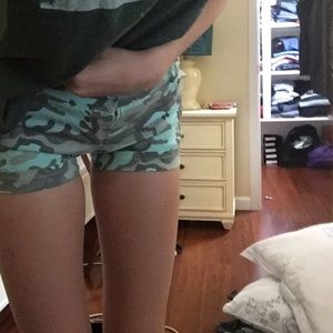A pair of camouflage shorts with a belt.