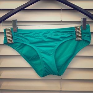 Turquoise swimsuit bottoms with gold accessories