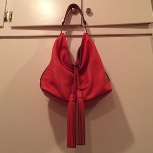 Red orange slouchy tote bag with tassel detail.