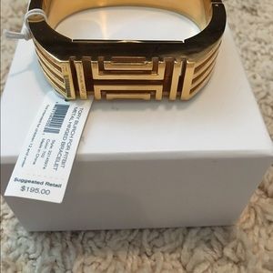 Tory Burch gold hinged fit bit bracelet.