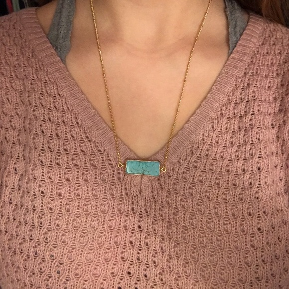 A gold chain necklace with a teel stone