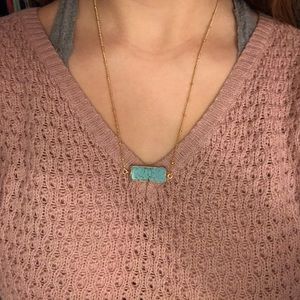 A gold chain necklace with a teel stone