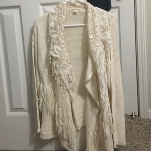 Off-white cardigan with lace and fringe.
