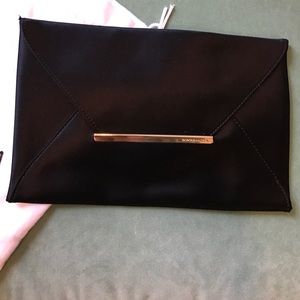 BCBG black clutch w/ gold bar accent. NWOT. Silk