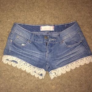 Light wash jean shorts with lace trim.