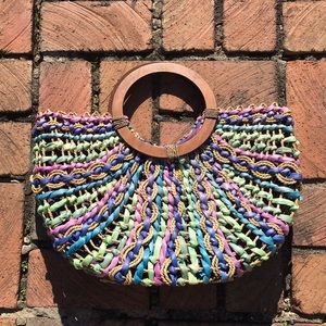 Brightly colored woven purse with wooden handles.