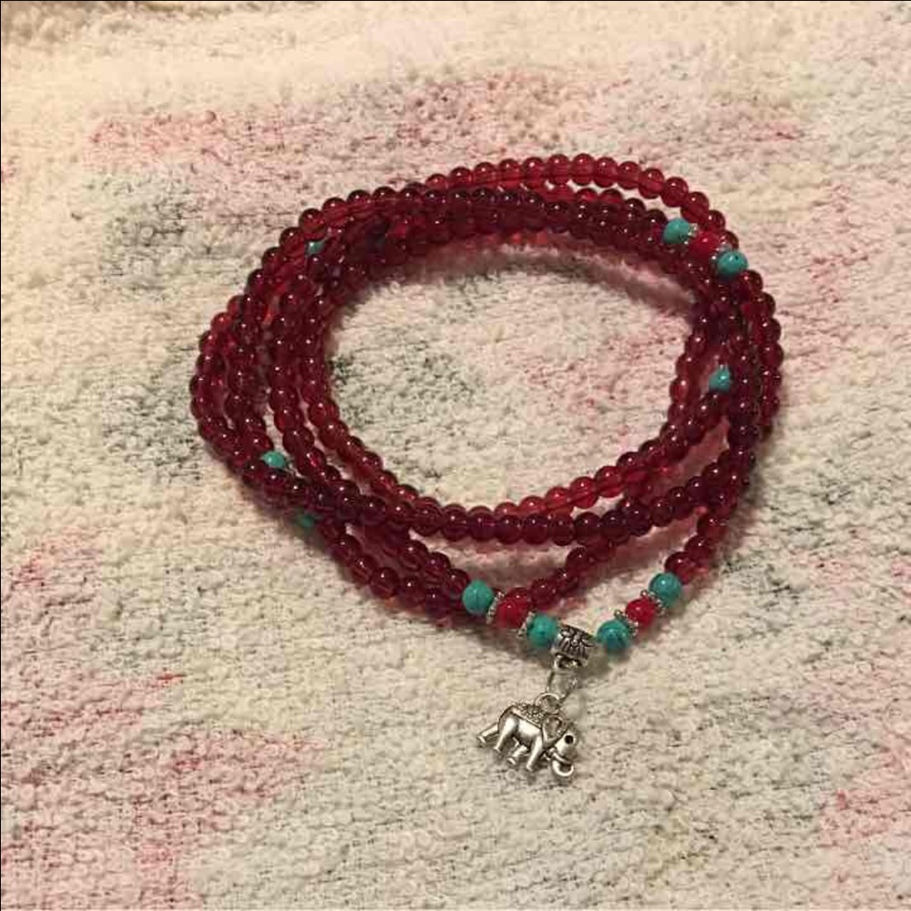 Read beaded bracelet with elephant pendant.