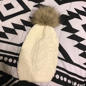 A knit hat with a poof on top.