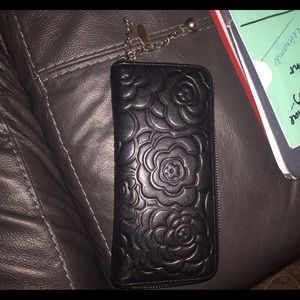 Black zip-up wallet with flower design.