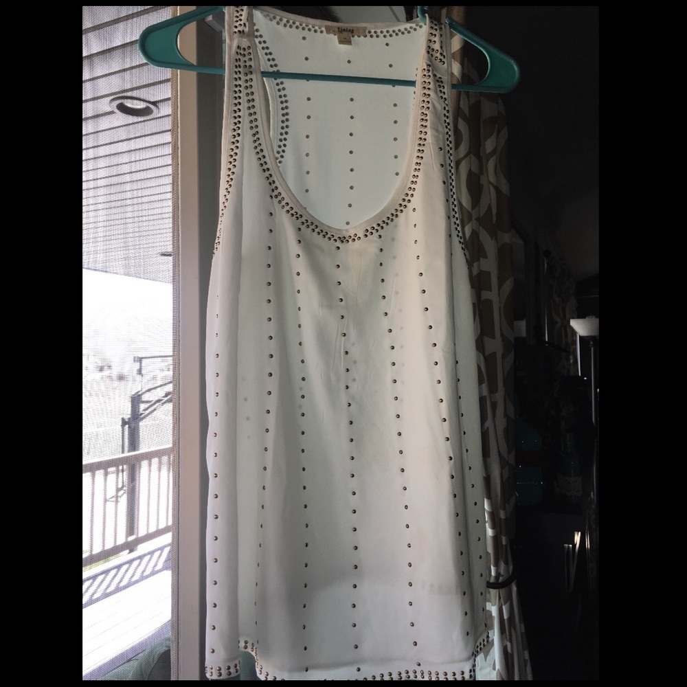 White blouse with gold beading around the shirt.