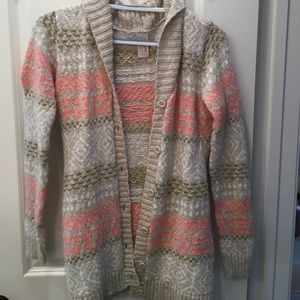 A pink, cream, and gold button-up sweater.