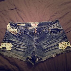 Blue jean shorts with decorative lace like patches