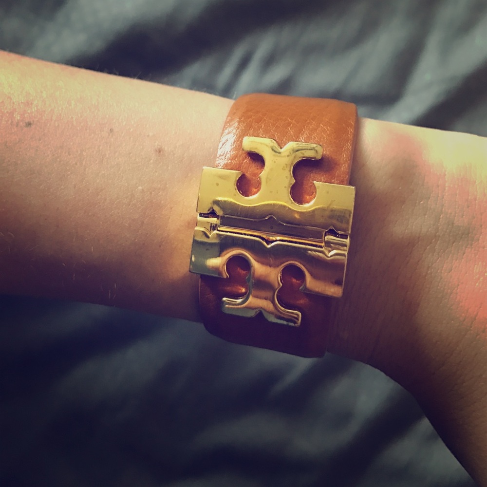 Tory Burch gold emblem bracelet on a brown band