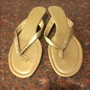 Gold leather flip flop sandals.