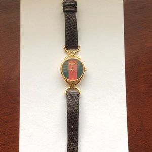 Round gold Gucci watch with black leather straps