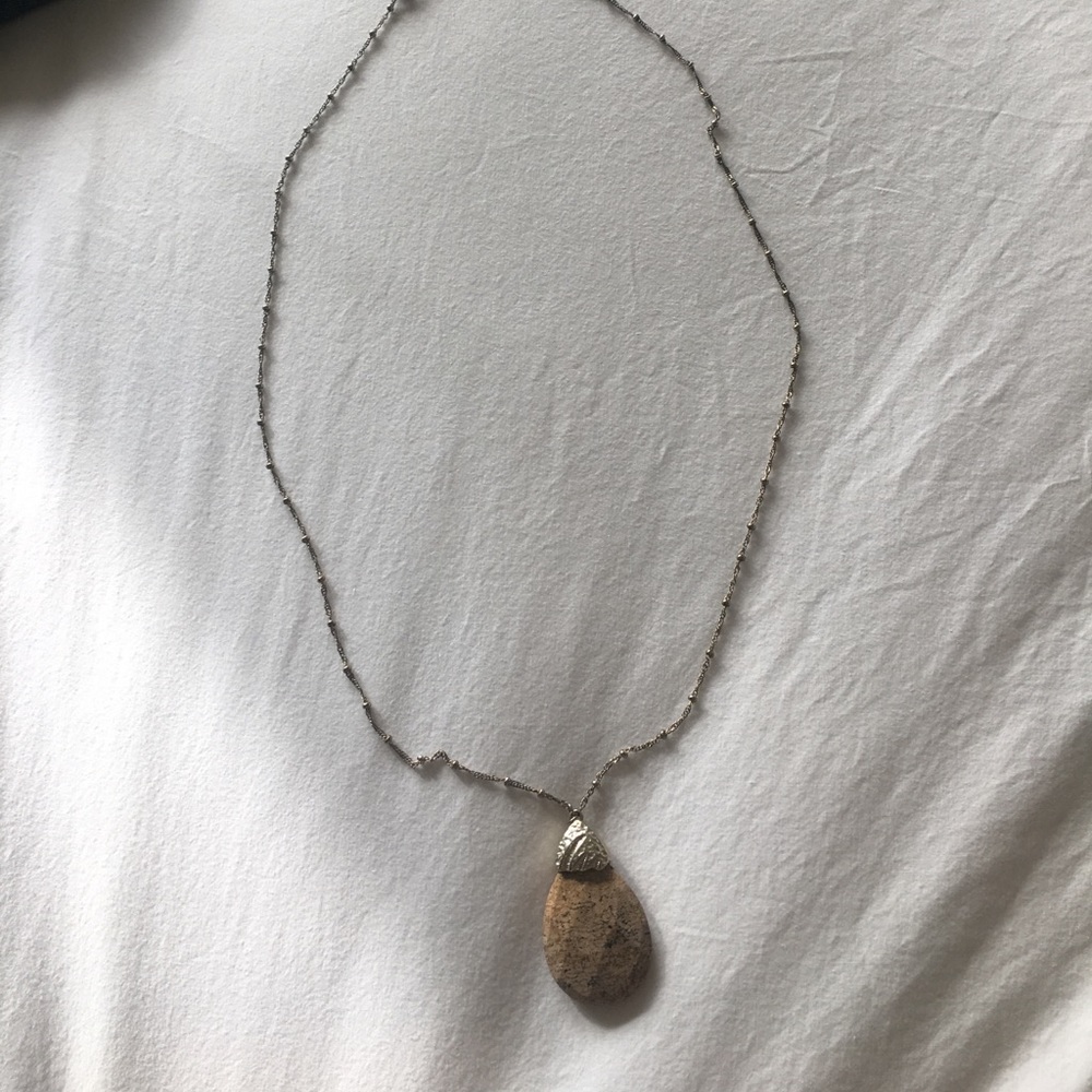 Long gold necklace with a brown stone