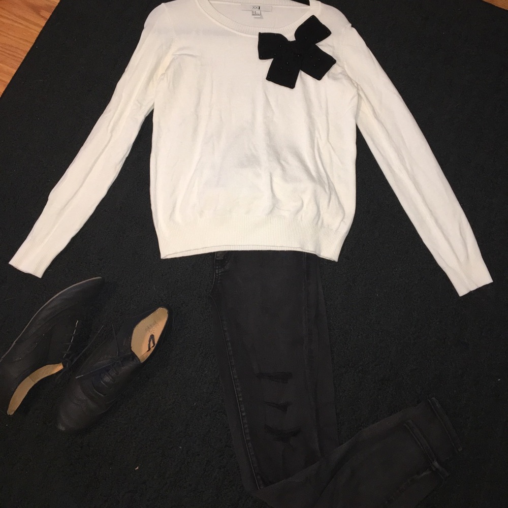 White sweater with black bow around collar
