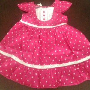 Pink baby dress with hearts and lace detailing.