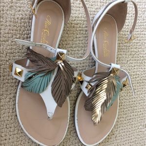 White flat sandals with gold studs and feathers