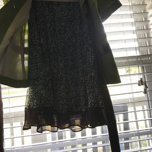 Green jacket with brown tie & multi colored skirt.