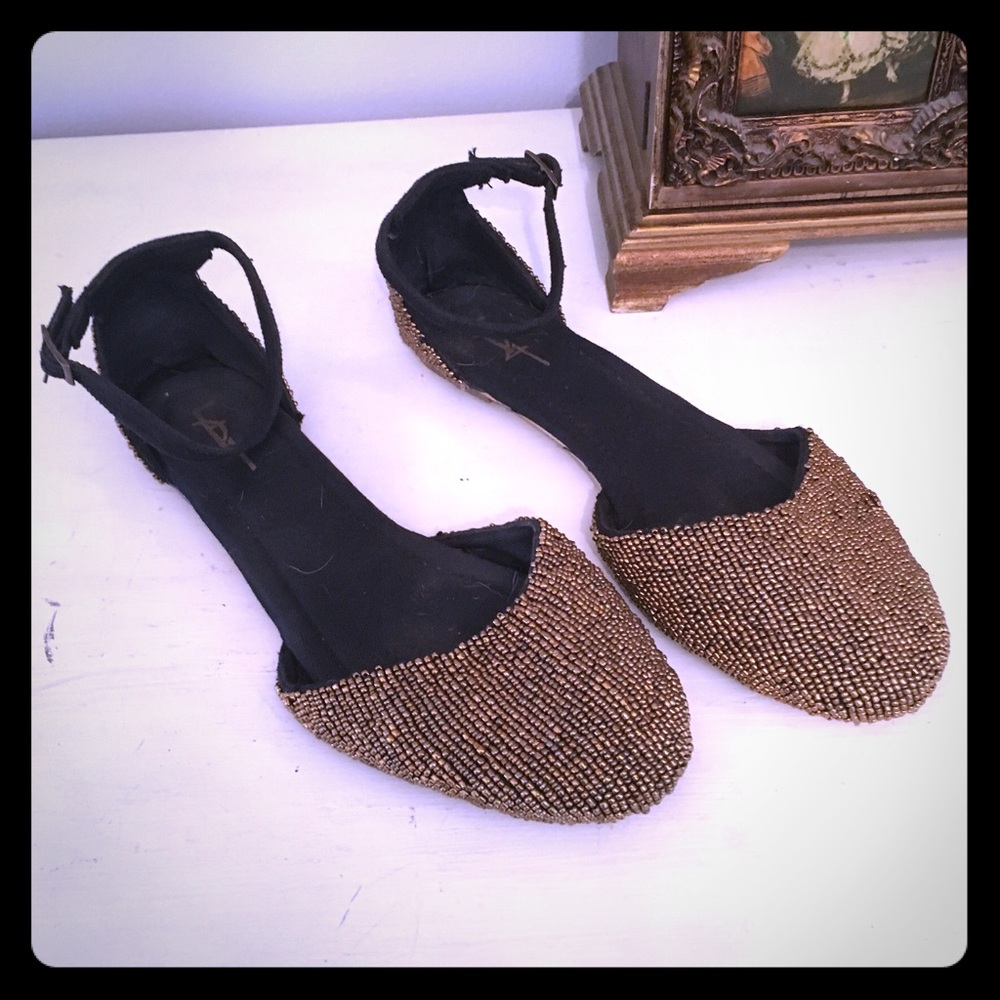 Gold beaded flats with ankle strap.