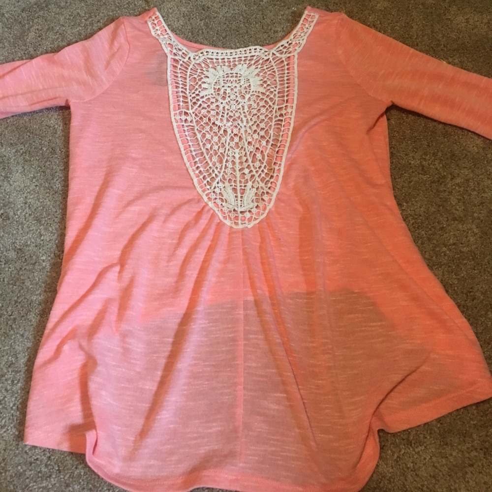 An orange high low shirt with a lace back