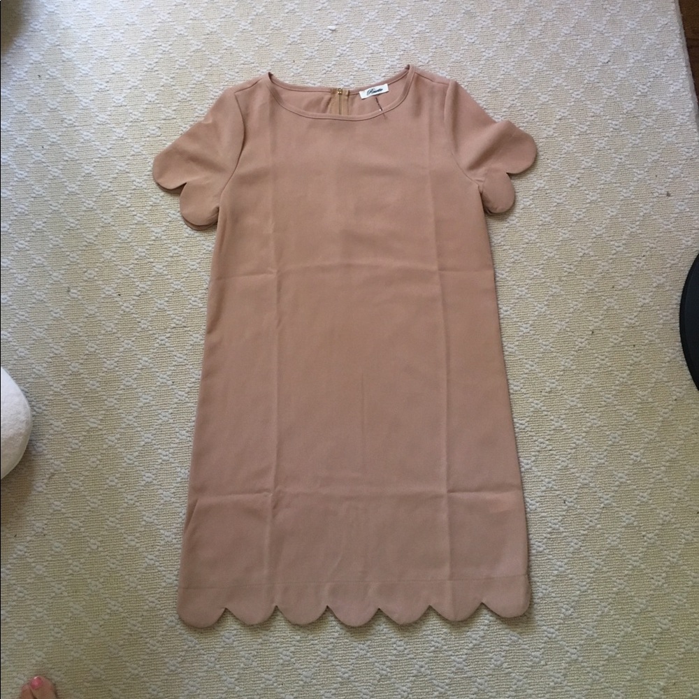 Nude shift dress with scalloped sleeves and hem.