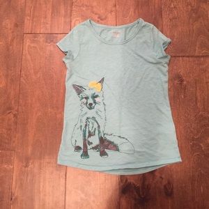 A teal shirt with a  fox and yellow bow on top