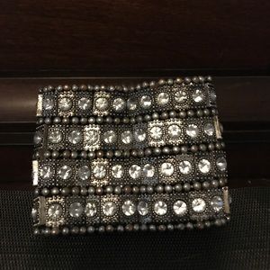 A thick dark metal bracelet with clear stones.