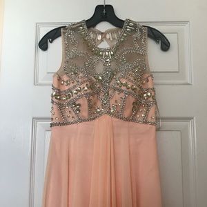 Long, light pink prom dress with jewel detailing.