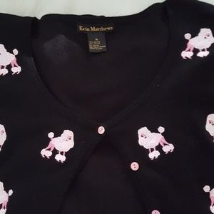 Black sweater with pink poodles stitched on front.